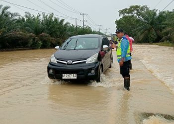 Respons Cepat Laporan Call Center 110, Polsek Padang Tualang Atur Lalu Lintas di Jalan Sumur Bor yang Tergenang Air