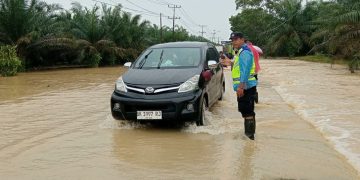 Respons Cepat Laporan Call Center 110, Polsek Padang Tualang Atur Lalu Lintas di Jalan Sumur Bor yang Tergenang Air